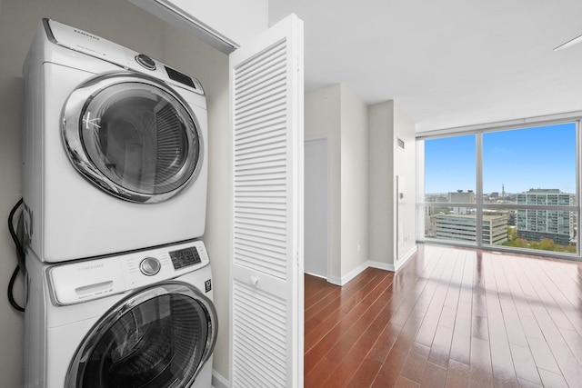 laundry room featuring stacked washing machine and dryer, baseboards, and dark wood-type flooring