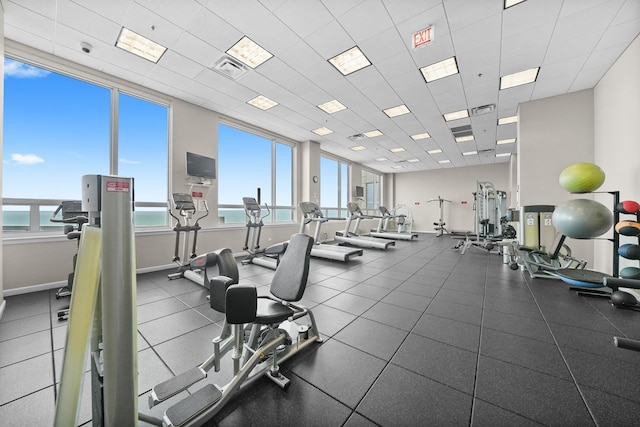 gym with a water view, baseboards, and a paneled ceiling
