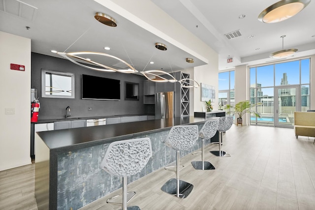 kitchen featuring dark countertops, stainless steel appliances, a sink, light wood-type flooring, and recessed lighting