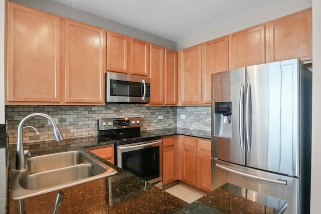 kitchen featuring stainless steel appliances, a sink, light brown cabinetry, and tasteful backsplash