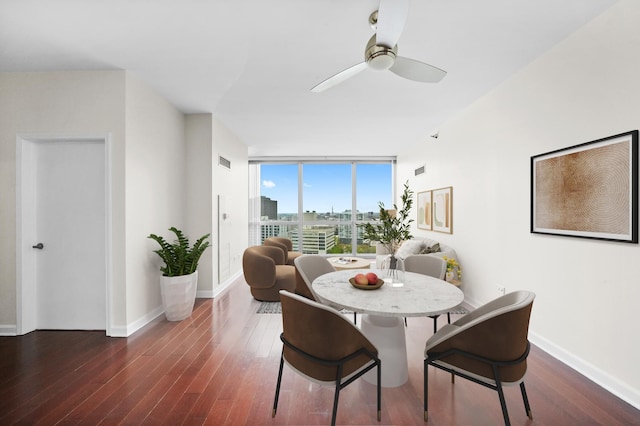dining area with wood finished floors, ceiling fan, a wall of windows, and baseboards