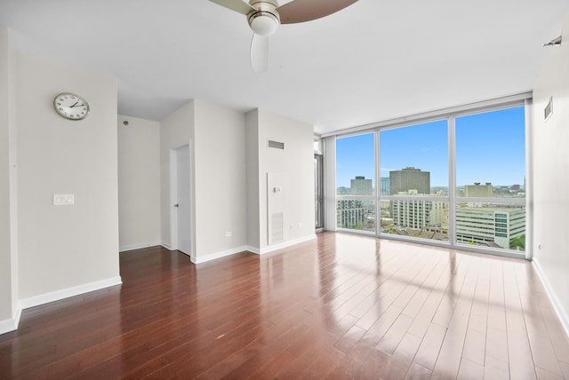 unfurnished living room with wood finished floors, floor to ceiling windows, ceiling fan, baseboards, and a view of city