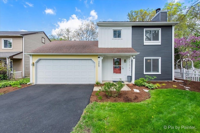 traditional-style home with a chimney, an attached garage, driveway, and board and batten siding