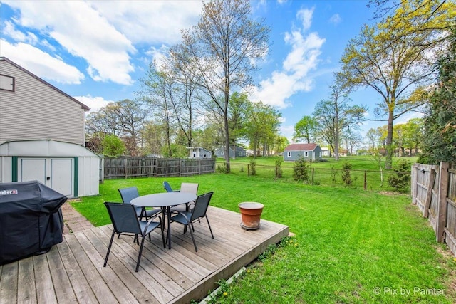 deck featuring outdoor dining space, a storage unit, and an outbuilding