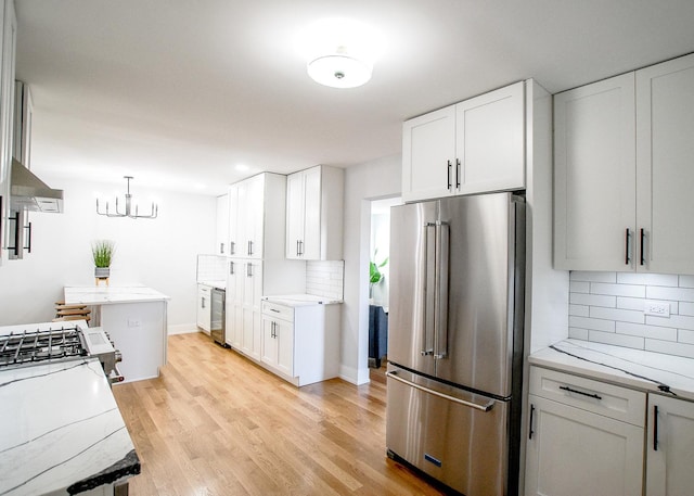 kitchen featuring high end refrigerator, tasteful backsplash, white gas range oven, and light wood-type flooring