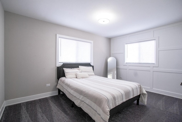 bedroom with multiple windows, dark carpet, and baseboards