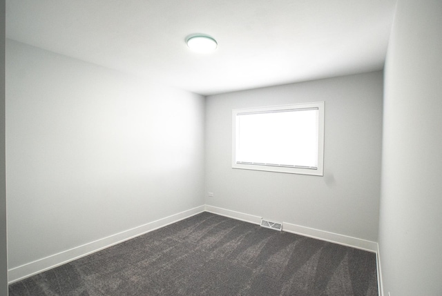 unfurnished room featuring dark colored carpet and baseboards