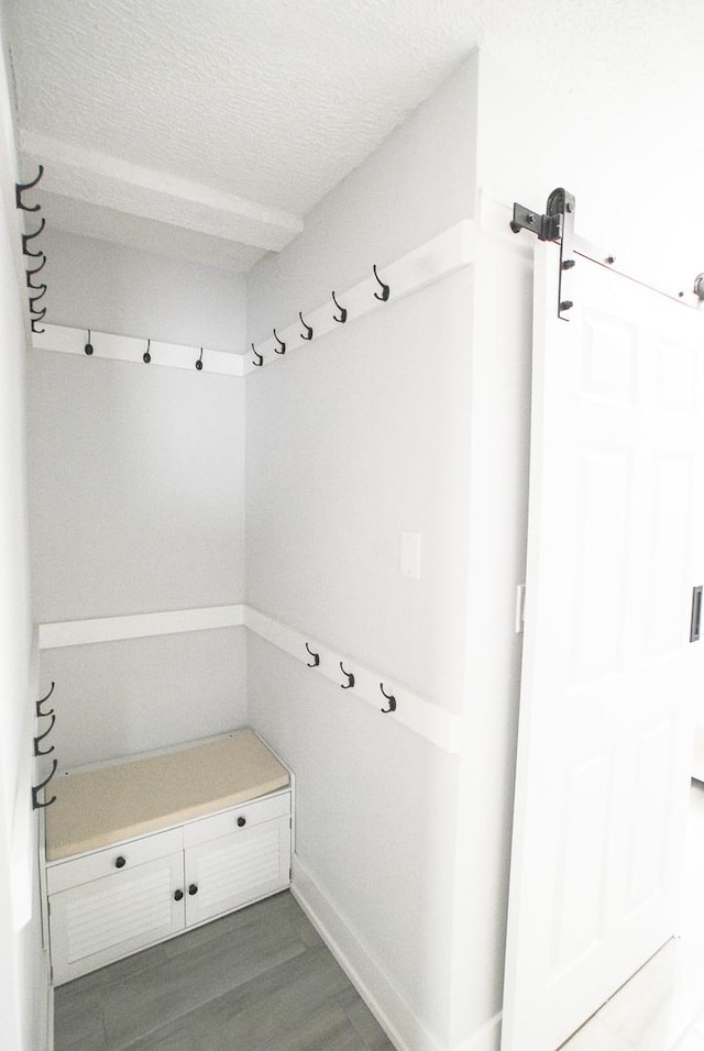 mudroom featuring a barn door, wood finished floors, and a textured ceiling