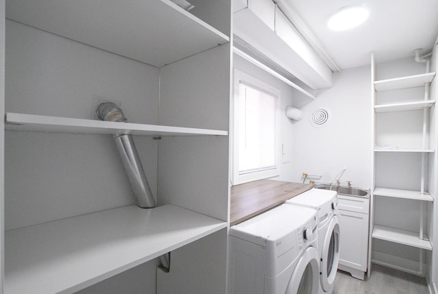 washroom with washing machine and dryer, a sink, and light wood-style flooring