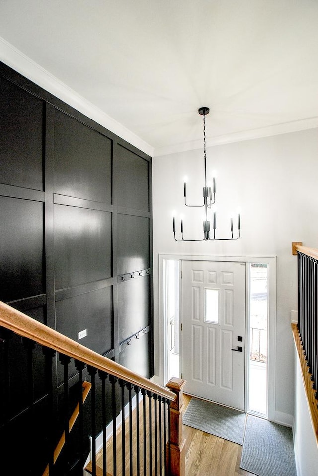 foyer entrance with a chandelier, light wood-type flooring, stairs, and ornamental molding