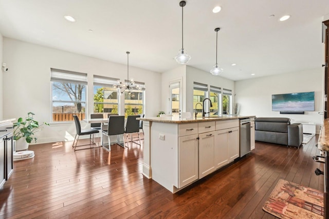 kitchen with stainless steel dishwasher, open floor plan, a sink, dark wood-type flooring, and plenty of natural light