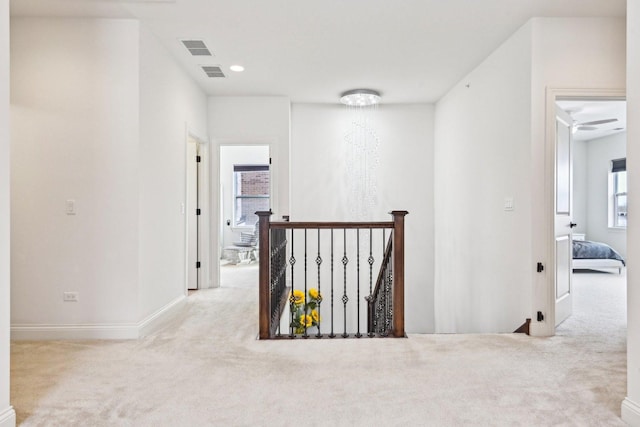 corridor with an upstairs landing, carpet floors, and baseboards