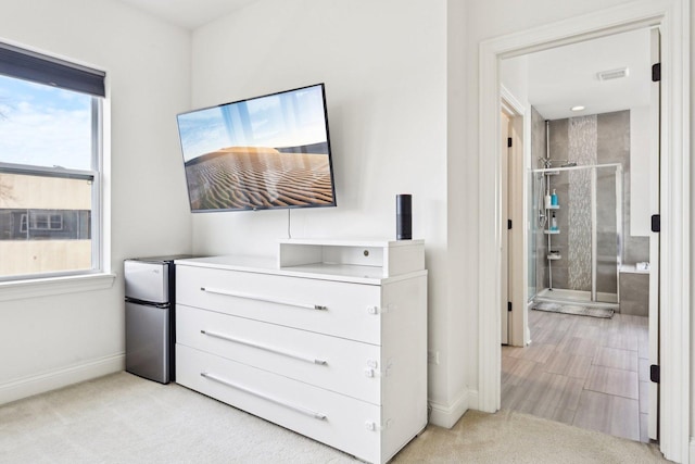 bedroom featuring freestanding refrigerator, baseboards, and light carpet