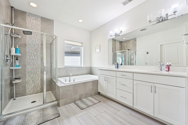 bathroom with a stall shower, a bath, double vanity, and recessed lighting