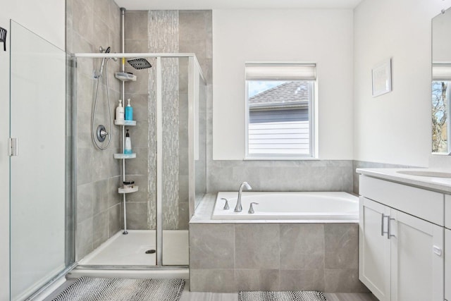 bathroom with a stall shower, a bath, and vanity
