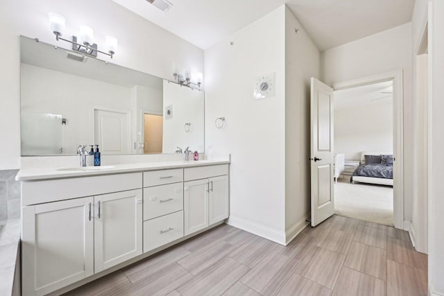 ensuite bathroom featuring double vanity, baseboards, and wood tiled floors