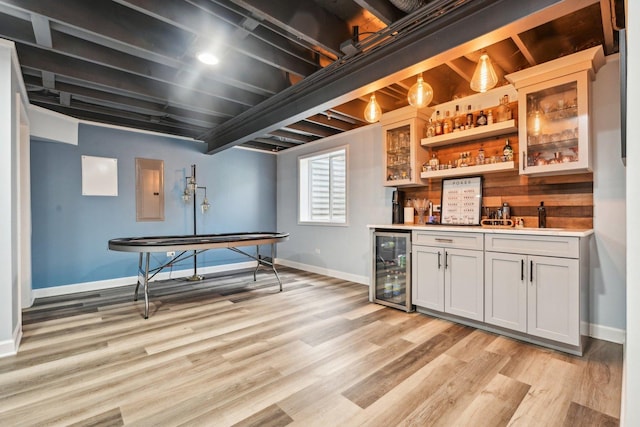 indoor wet bar featuring wine cooler, baseboards, and light wood finished floors