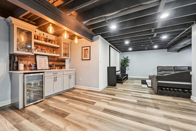 indoor wet bar featuring wine cooler, baseboards, and light wood-style flooring