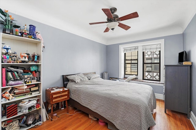 bedroom featuring wood finished floors, a ceiling fan, ornamental molding, and baseboards