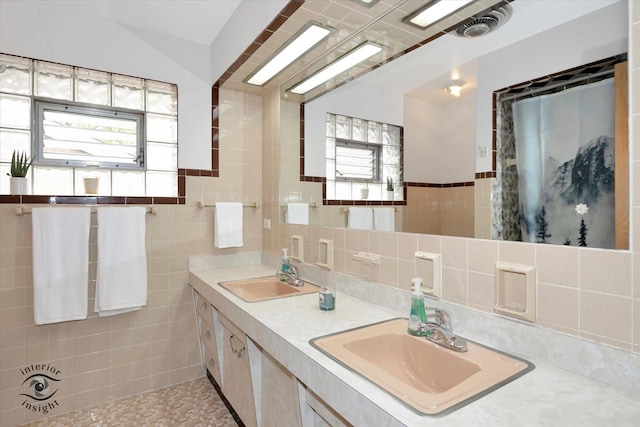 full bathroom with plenty of natural light, tile walls, double vanity, and wainscoting
