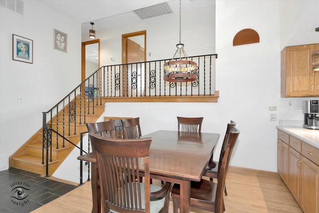 dining space featuring a chandelier, light wood-style floors, and stairs