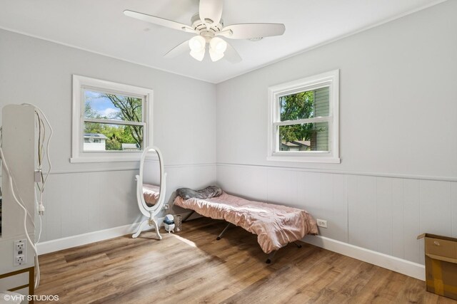 1011 Beverly Dr, Wheeling, IL 60090 - bedroom featuring multiple windows, wood finished floors, a wainscoted wall, ceiling fan, and a decorative wall