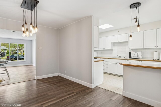 1011 Beverly Dr, Wheeling, IL 60090 - kitchen featuring white cabinets, light countertops, wood finished floors, baseboards, and pendant lighting