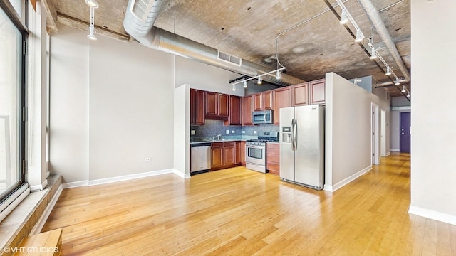 kitchen featuring stainless steel appliances, light wood-style floors, baseboards, tasteful backsplash, and track lighting