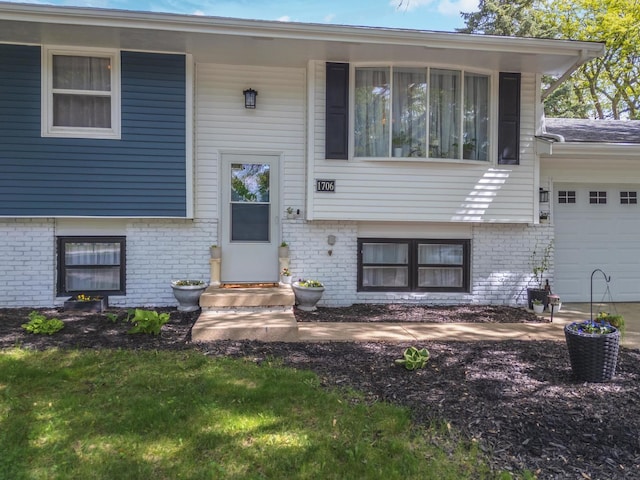 raised ranch featuring brick siding, an attached garage, and entry steps
