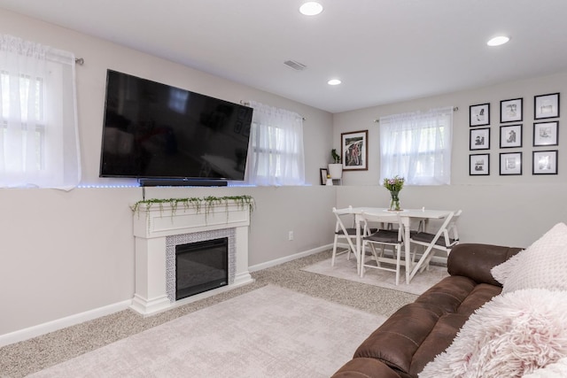 carpeted living area with recessed lighting, a tiled fireplace, and baseboards