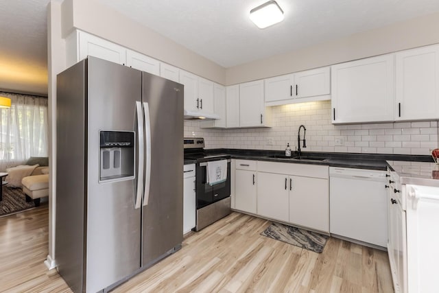 kitchen featuring stainless steel appliances, a sink, light wood-type flooring, decorative backsplash, and white cabinetry
