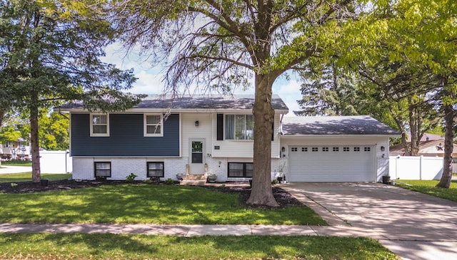 raised ranch featuring a garage, concrete driveway, and brick siding