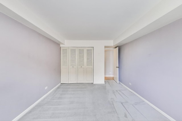 unfurnished bedroom with baseboards, a closet, and light carpet