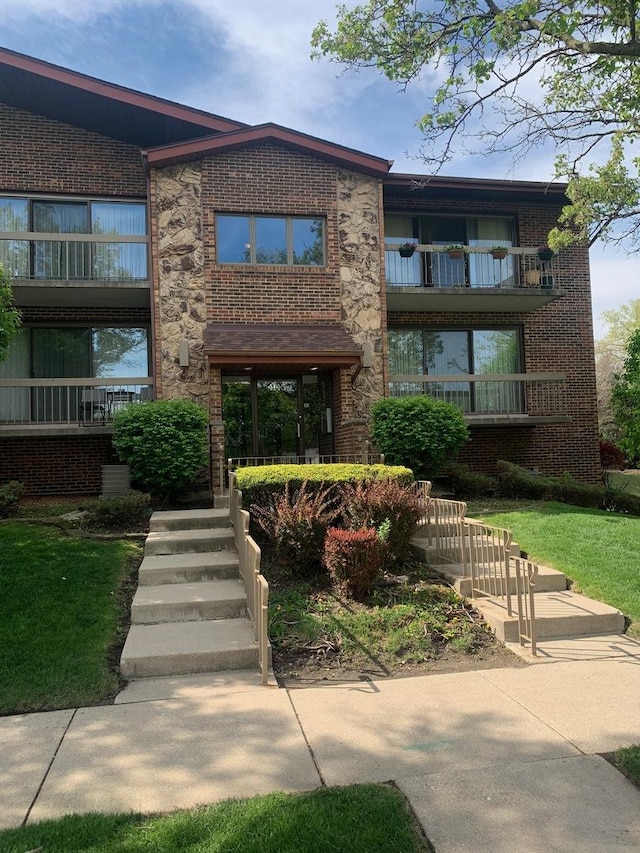 view of front of property with brick siding and a balcony