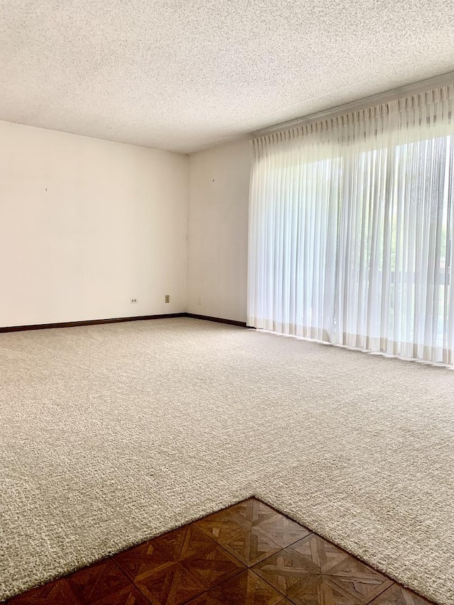 spare room featuring carpet floors, a textured ceiling, and baseboards