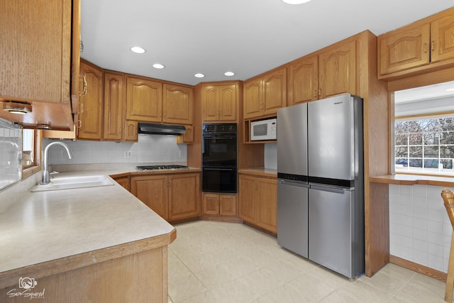 kitchen with freestanding refrigerator, a sink, gas stovetop, under cabinet range hood, and white microwave
