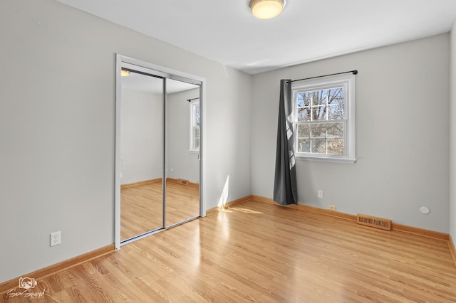 unfurnished bedroom featuring wood finished floors, a closet, and baseboards