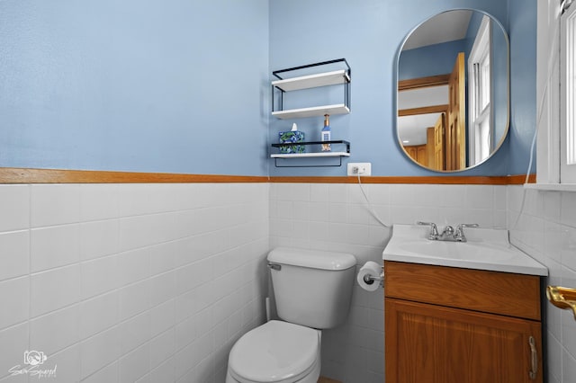 bathroom with tile walls, toilet, vanity, and wainscoting