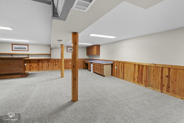 finished below grade area with wainscoting, light carpet, and wooden walls