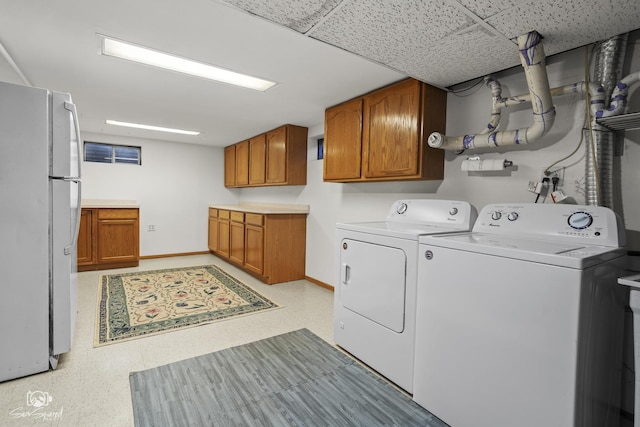 washroom featuring cabinet space, baseboards, washing machine and clothes dryer, and light floors