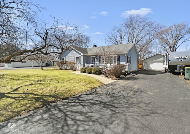 ranch-style house with covered porch, an outbuilding, a detached garage, a front yard, and a chimney