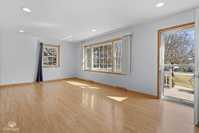 unfurnished living room with healthy amount of natural light, wood finished floors, baseboards, and recessed lighting