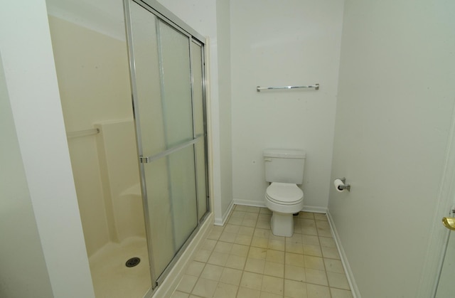 bathroom with a shower stall, baseboards, tile patterned floors, and toilet