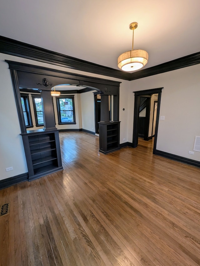 7411 S Champlain Ave, Chicago, IL 60619 - unfurnished dining area featuring crown molding, baseboards, wood finished floors, arched walkways, and decorative columns