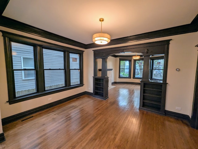 7411 S Champlain Ave, Chicago, IL 60619 - unfurnished dining area featuring decorative columns, arched walkways, ornamental molding, wood finished floors, and baseboards