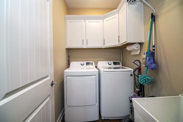 clothes washing area featuring washing machine and dryer and cabinet space