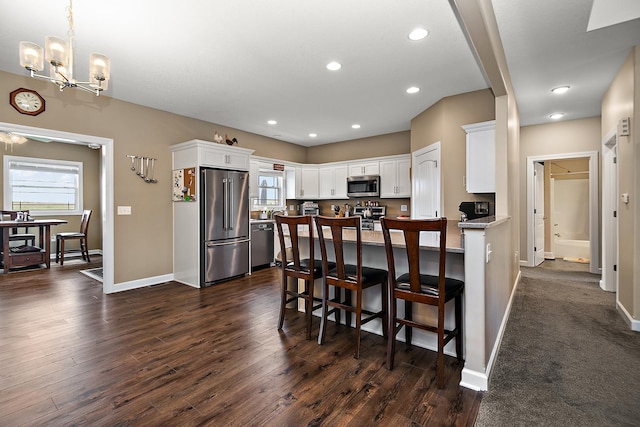 kitchen featuring stainless steel appliances, healthy amount of natural light, white cabinetry, a chandelier, and recessed lighting