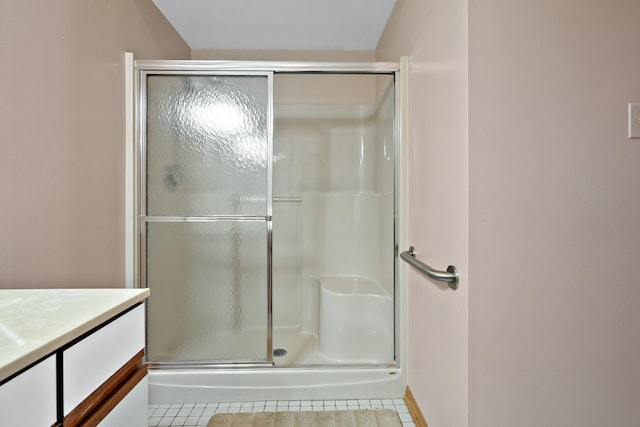 bathroom with a shower with shower door, vanity, and tile patterned floors