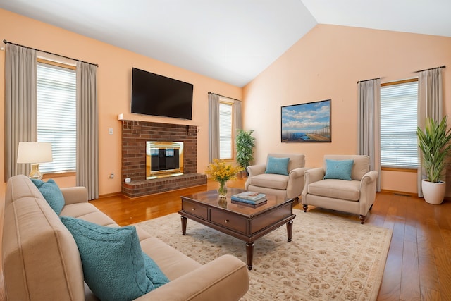 living area featuring lofted ceiling, hardwood / wood-style floors, and a brick fireplace