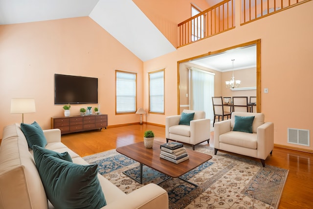 living area with wood finished floors, a chandelier, high vaulted ceiling, and baseboards